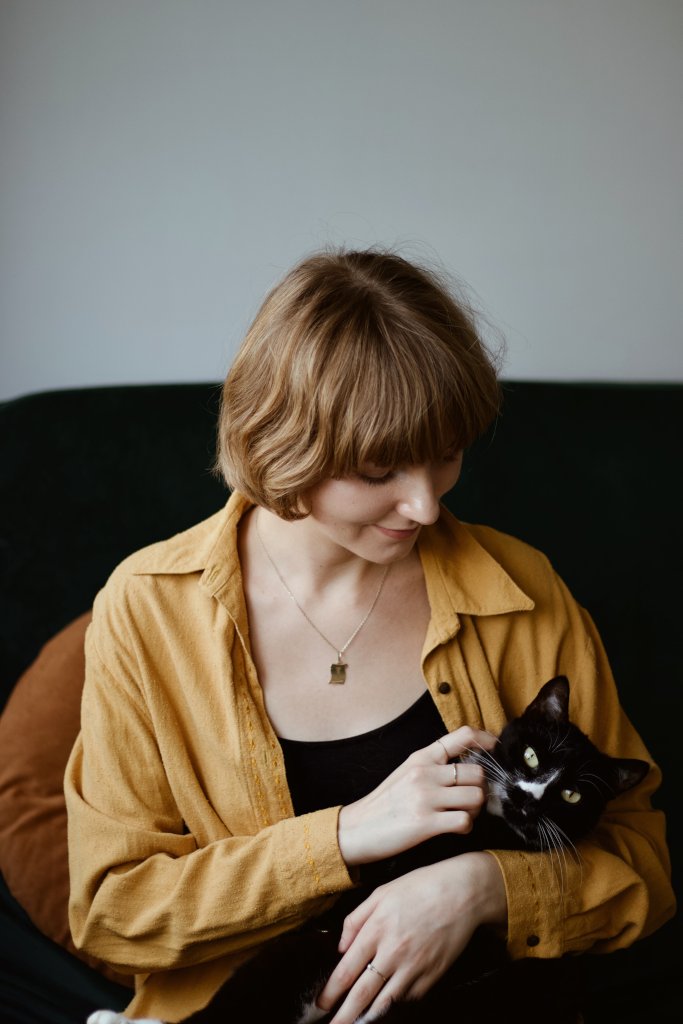 Izabela Stańczyk felinoterapeutka czule przytulająca czarnego kota na kolanach. Profesjonalna felinoterapia Kraków wspierająca dobrostan emocjonalny człowieka.