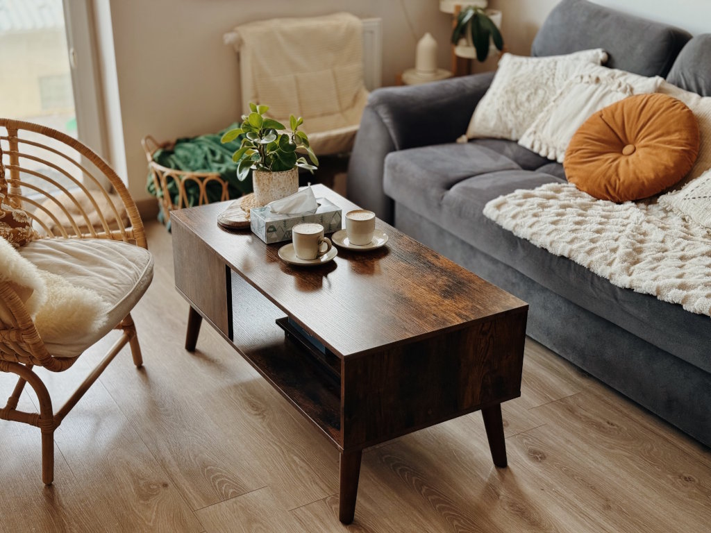 Jasny, przytulnie urządzony gabinet psychologiczny z drewnianym stolikiem kawowym i szarą sofą z poduszkami. Konsultacje psychologiczne dla dzieci, dorosłych i seniorów – Kraków, Prądnik Biały.